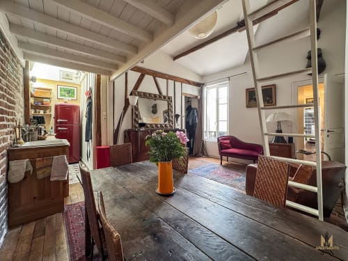 Appartement Del Sarte à Paris Montmartre avec table à manger, poutres apparentes, accents rouges et séjour ouvert