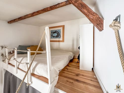 Chambre thématique nautique aux Apartments Montmartre Paris avec lit à baldaquin blanc, détails de cordes et poutres en bois