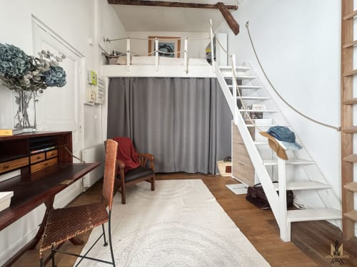 Studio Del Sarte à Montmartre Paris avec lit mezzanine, escalier blanc, coin salon et bureau en bois