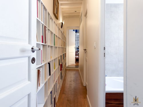 Couloir avec rangements intégrés blancs aux Appartements Montmartre, appartement Del Sarte à Paris, menant à la salle de bain