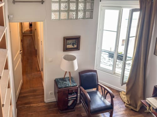 Coin salon cosy de l'appartement Del Sarte aux Montmartre Apartments, Paris avec fauteuil, lampadaire et portes-fenêtres donnant sur