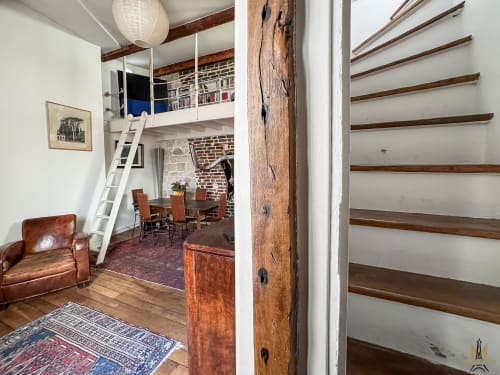 Loft Delacroix à Montmartre avec poutres apparentes, mezzanine, mobilier cuir et escalier en bois, Paris