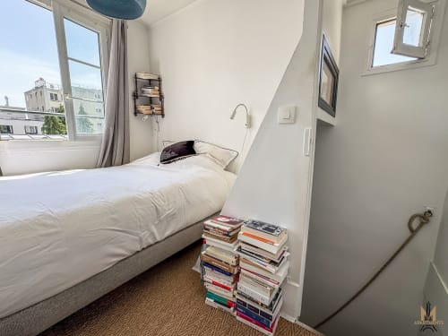 Chambre des Appartements Montmartre Del Sarte à Paris avec lit, livres empilés, vue fenêtre et décoration minimaliste