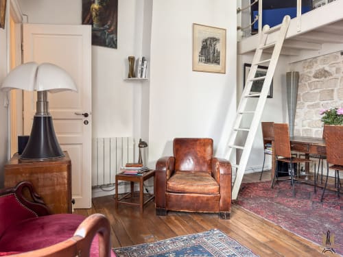 Spacieux séjour de l'appartement Del Sarte à Montmartre, avec fauteuil en cuir vintage, mobilier en bois et loft