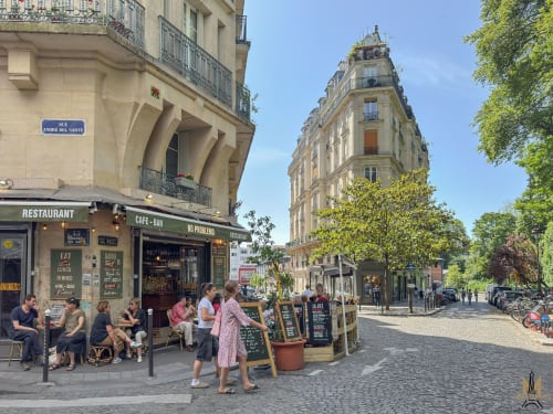 Rue André del Sarte à Montmartre avec café traditionnel, immeubles historiques et rue bordée d'arbres