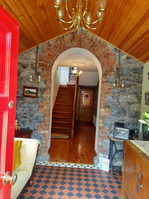 Knockaderry House entrance hall with brick archway, wooden staircase, and checkered tile floor in Ennis, Ireland
