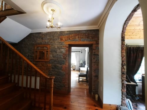 Knockaderry House hallway with exposed brick walls, wooden staircase, and archway leading to bedroom, Ennis