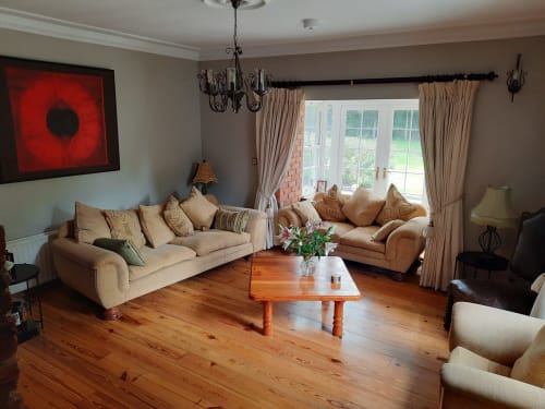 Spacious living room at Knockaderry House B&B in Ennis with beige sofas, wooden coffee table, and large windows overlooking