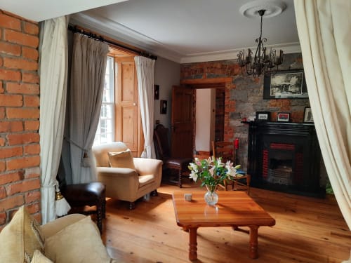 Knockaderry House B&B lounge with exposed brick, fireplace, wooden furniture and fresh flowers in Ennis