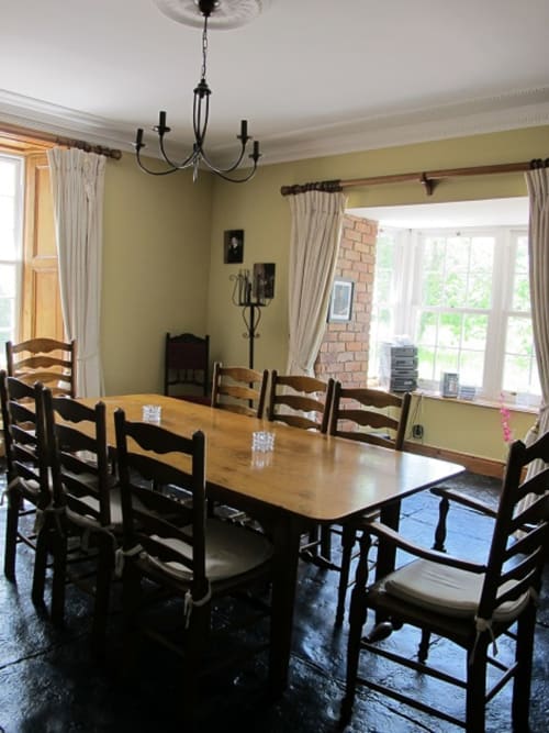 Elegant dining room at Knockaderry House B&B in Ennis with wooden table, black ladder-back chairs, and yellow walls