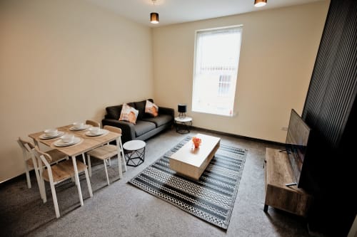 Modern apartment living and dining area at The JS Apartments in Blackburn with sofa, dining table, and city view window