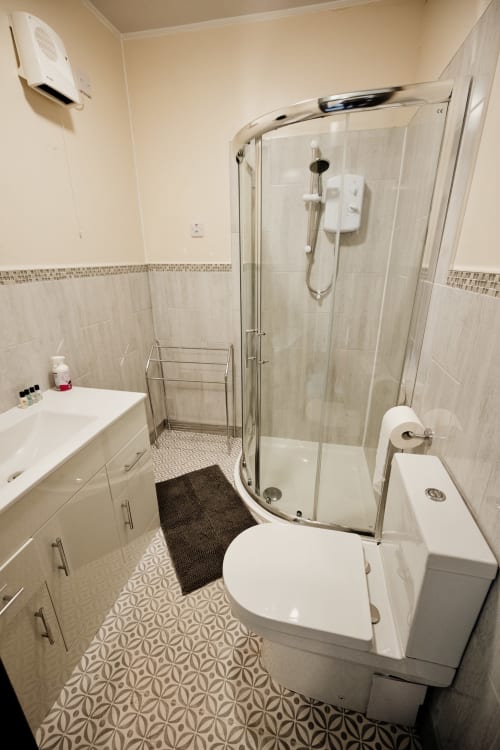 Modern bathroom in The Residence by JS Apartments, Blackburn, featuring walk-in shower, white vanity, and patterned tile