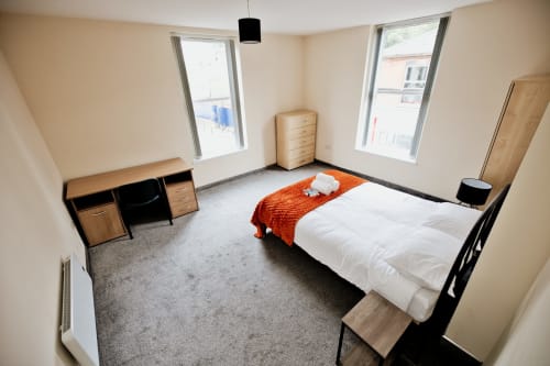 Modern bedroom at The Residence by JS Apartments, Blackburn with double bed, work desk, and city views from windows
