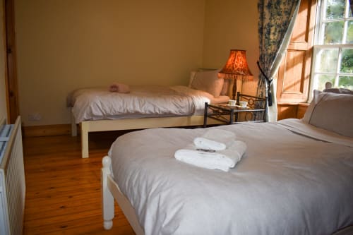 Twin beds with white towels in a bright bedroom at Knockaderry House B&B in Ennis, Ireland, featuring wooden floors and