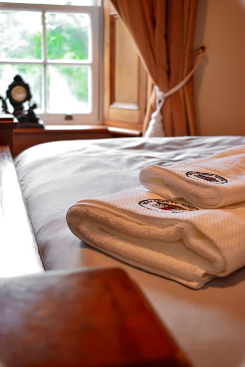 Folded towels on bed at Knockaderry House B&B in Ennis with window and curtains