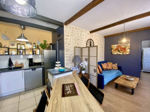 Intérieur de cottage bohème avec cuisine ouverte, canapé bleu, poutres apparentes et accents colorés à Sarlat