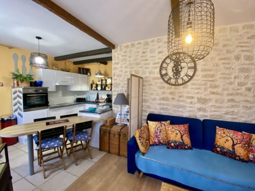 Séjour ouvert et lumineux du gîte Le Cocon Boheme à Ô Clair De Lune, Sarlat, avec canapé bleu, cuisine et décoration bohème