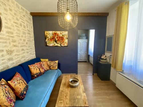 Salon douillet du gîte Le Cocon Boheme à Ô Clair De Lune, Sarlat avec canapé bleu, coussins colorés et table en bois