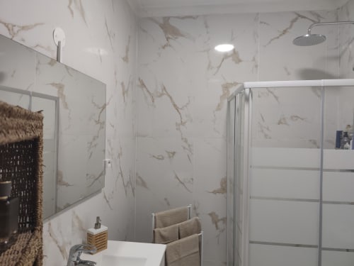 Banheiro moderno com mármore na Albufeira Inn, com box de chuveiro, espelho, pia e toalheiro aquecido