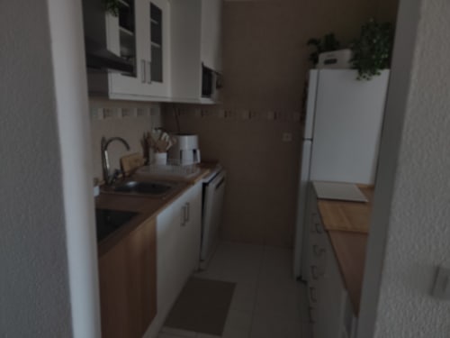 Cozinha compacta no apartamento T1 Albufeira Inn com armários brancos, bancada castanha, pia, fogão e frigorífico