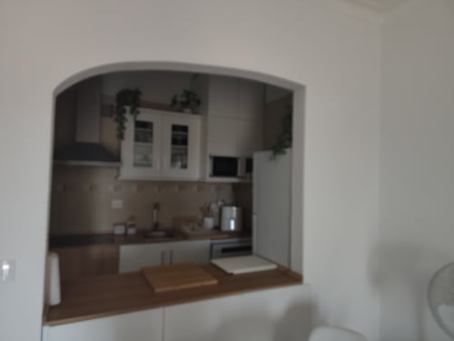 Cozinha moderna com bancadas de madeira no apartamento T1 Albufeira Inn, mobiliário branco e layout compacto