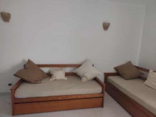 Dois camas de madeira com roupa de cama creme e almofadas em quarto claro do Albufeira Inn, apartamento Edifício Elimar 1