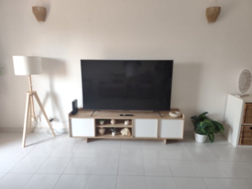 Apartamento estúdio moderno na Albufeira Inn com TV, móvel de entretenimento em madeira, luminária de tripé e planta em vaso na sala.