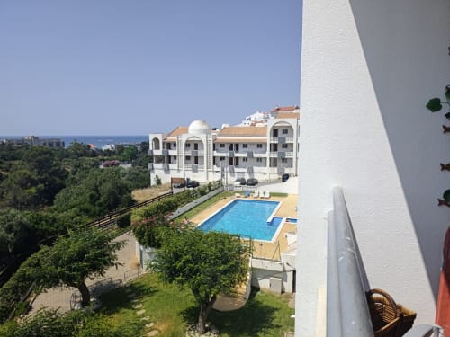 Vista da varanda do Albufeira Inn com piscina, edifícios brancos, jardins exuberantes e horizonte do mar em Portugal