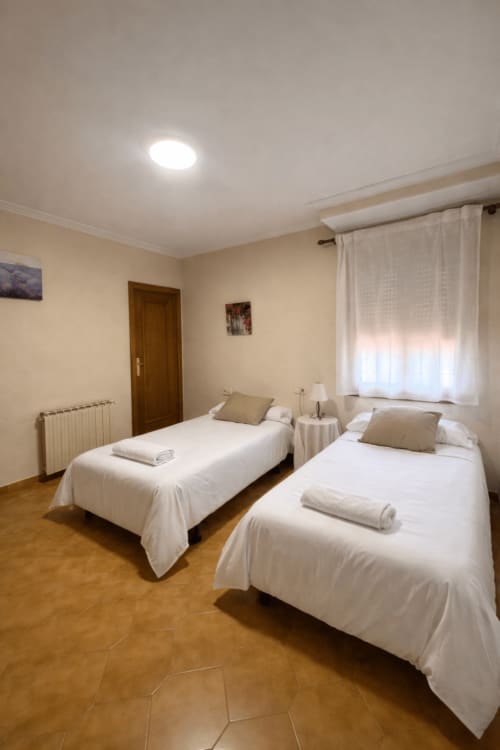 Habitación doble en Casa Rural Finca El Olivar con dos camas, ropa de cama blanca, suelo de madera y luz natural