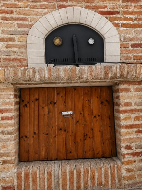 Edificio rústico de ladrillo en Casa Rural Finca El Olivar con puerta de madera y ventana arqueada de horno