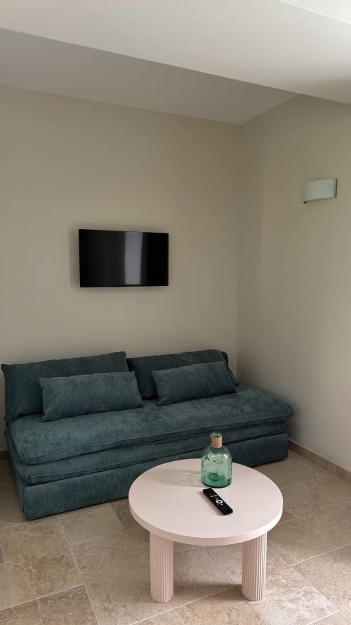 Chambre moderne du gîte Cloffy à Nouans-les-Fontaines avec canapé bleu-vert, télévision murale et table blanche ronde