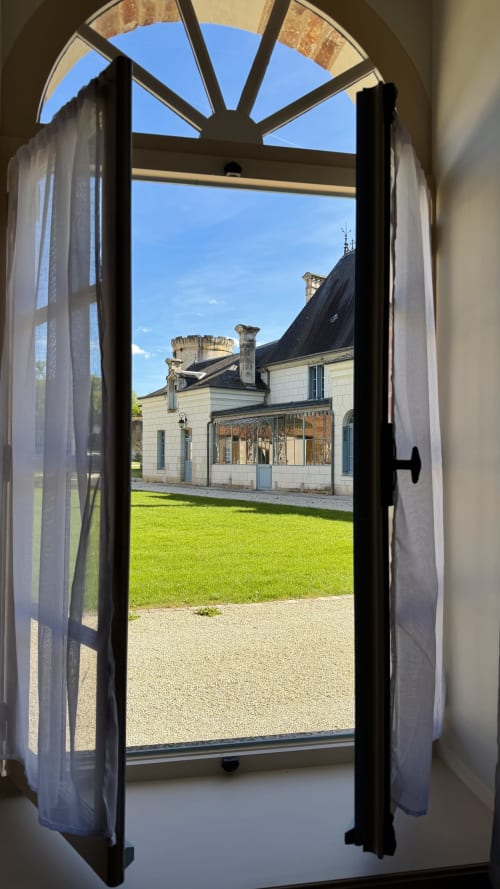 Portes noires ouvertes encadrant le cottage Cloffy avec pelouse soignée et tour à Nouans-les-Fontaines