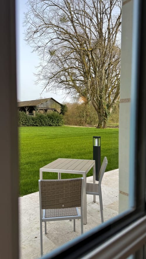 Terrasse du cottage Cloffy avec table à manger extérieure vue sur pelouse verdoyante et arbres nus à Nouans-les-Fontaines