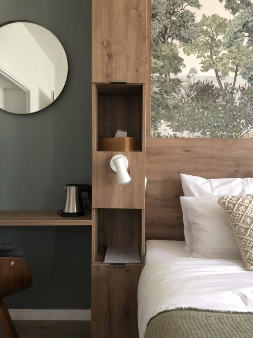 Modern bedroom at Les clés d'à côté with wooden partition, round mirror, white bedding, and botanical garden view wallpaper