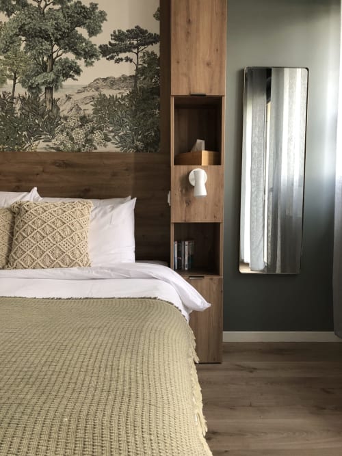 Cozy bedroom at Les clés d'à côté near Rouen with wooden headboard, botanical wallpaper, green bedding, and mirror