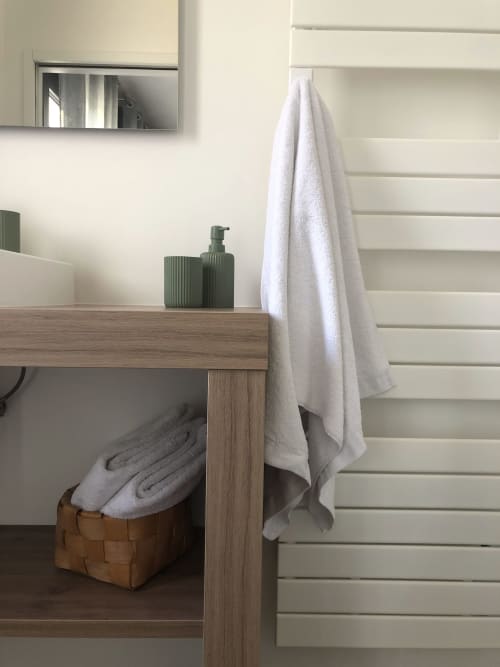 Modern bathroom vanity with white towels and green soap dispensers at Les clés d'à côté, Rouen