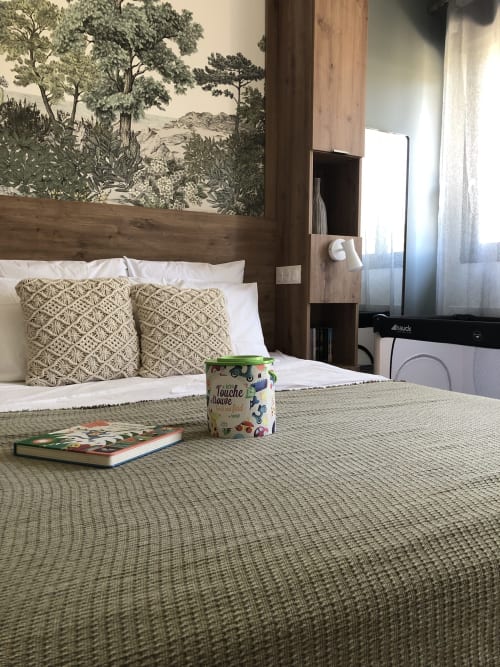 Cozy bedroom at Les clés d'à côté near Rouen with wooden headboard, patterned pillows, and garden view wallpaper