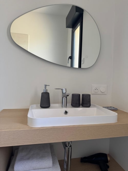 Lavabo rectangular blanco, grifo cromado y espejo ovalado en el cuarto de baño de la casa de huéspedes Les clés d'à côté cerca de Rouen