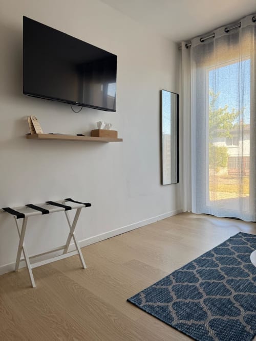 Habitación moderna en Les clés d'à côté cerca de Rouen con televisor pantalla plana, estantería de madera, soporte para equipaje y vista al jardín