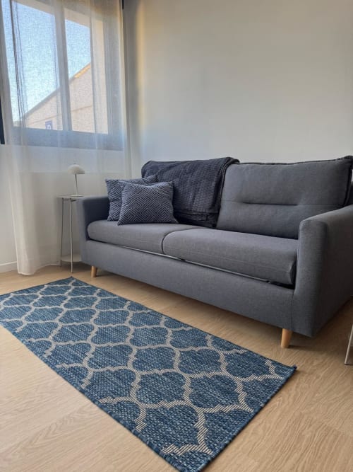 Sofá gris moderno con alfombra estampada en la habitación Les clés d'à côté cerca de Rouen, Francia