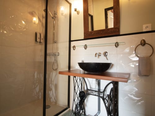 Salle de bain moderne à L'Ecrin des Roches avec vasque noire, meuble bois, douche à l'italienne et miroir décoratif