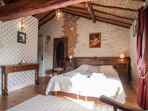 Chambre Bordeaux à L'Ecrin des Roches, Le Langon : chambre rustique avec poutres apparentes, murs en brique, lit en bois et élégante
