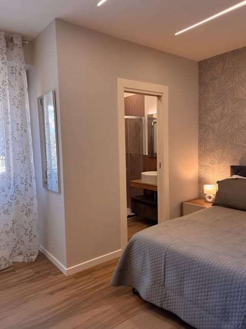Camera da letto moderna con bagno privato, pavimenti in legno e illuminazione contemporanea presso Anima Est B&B a Napoli