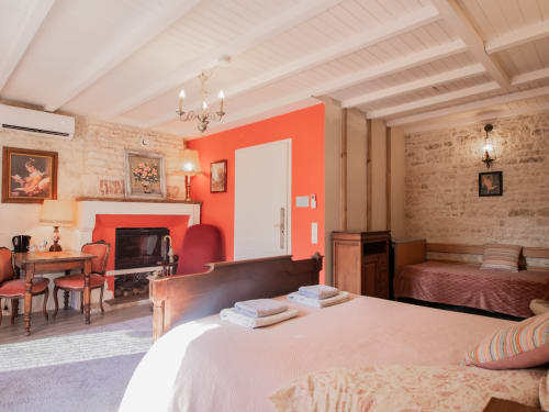 Chambre Corail à L'Ecrin des Roches : chambre accessible avec cheminée, murs couleur corail, poutres apparentes et mobilier d'époque