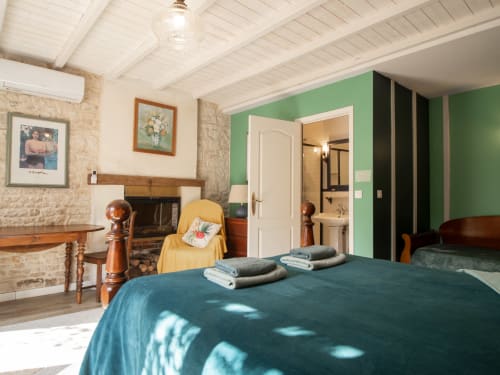 Chambre Verte Deluxe à L'Ecrin des Roches : lit bleu-vert, cheminée et mur d'accent vert