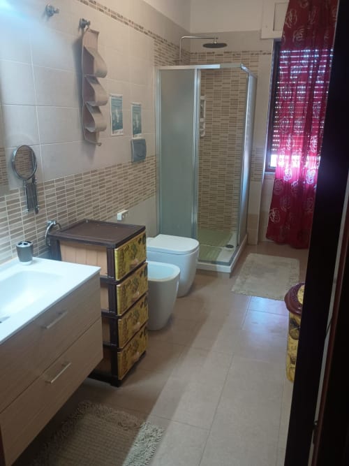 Bagno moderno in B&B S HOME, Napoli con lavabo bianco, toilette, doccia con box in vetro e mobili decorativi