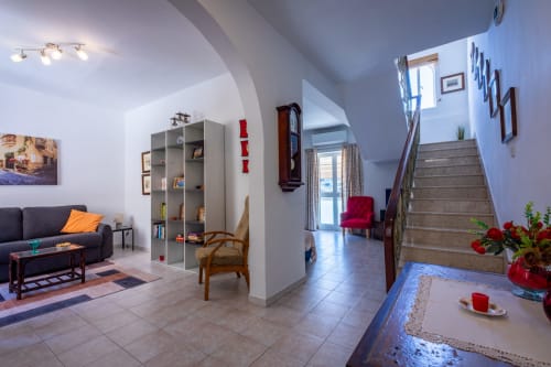 Zona living di una townhouse sul lungomare di Marsaskala con divano, scaffali, scale e vista sul mare a Wied il-Għajn, Malta