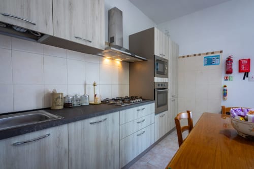 Cucina moderna nella casa a schiera fronte mare di Marsaskala con cabinetry bianca, top neri, fornello a gas e tavolo da pranzo