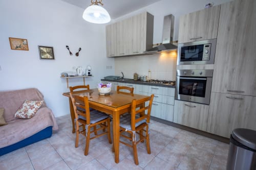 Zona cucina e sala da pranzo a pianta aperta in una townhouse fronte mare a Marsaskala con tavolo in legno e angolo cottura attrezzato