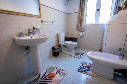 Bagno spazioso in casa sulla costa di Marsaskala con lavabo, WC, vasca e tappetini decorativi